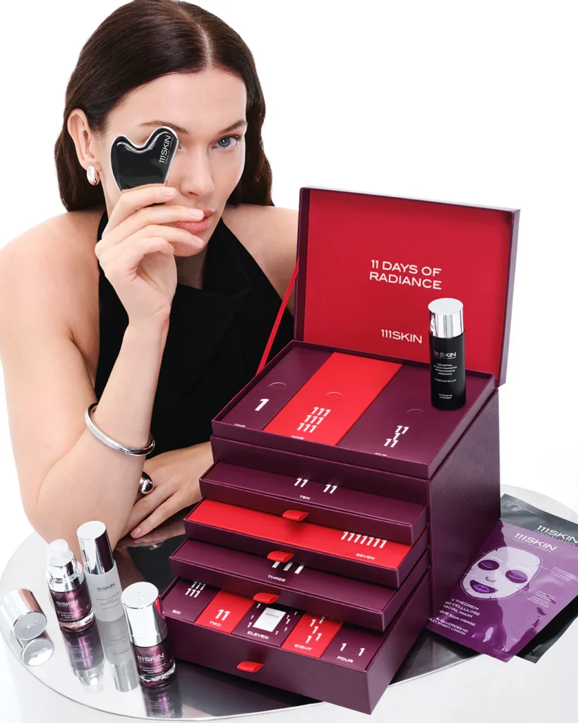 Una modelo posa con el gua sha y la caja del Calendario de adviento 111Skin 2025