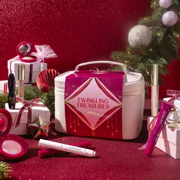 La bolsa neceser y algunos de los productos del Calendario de adviento Catrice 2025 en un fondo navideño.