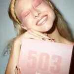 Una modelo posa sonriente con el Calendario de Adviento 3INA Makeup 2024