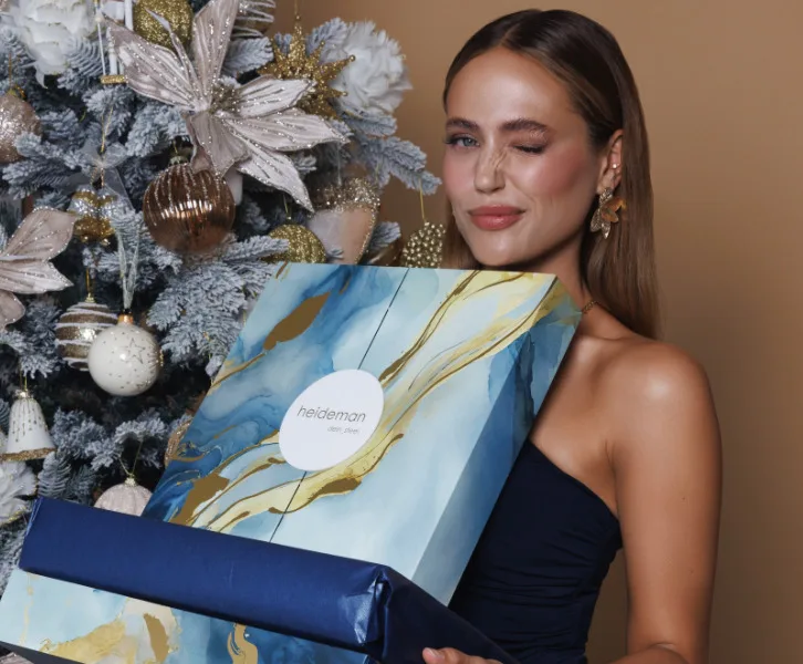 Una modelo guiña el ojo mientras sujeta el Calendario de Adviento Heideman 2024