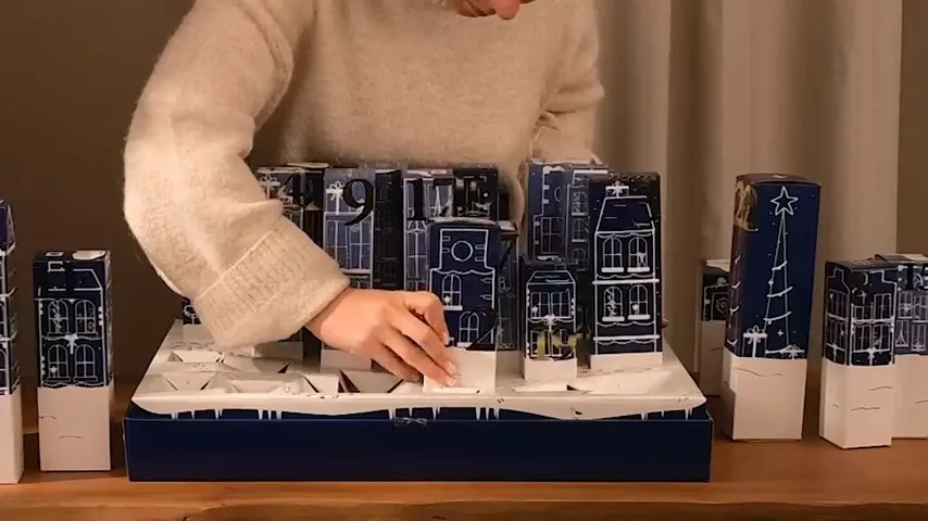 Una mujer monta la escena navideña del calendario 3D DIY de Jean & Len 2025