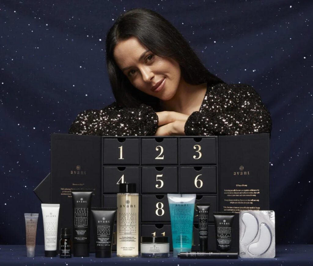 Una mujer posa con la caja y los productos del Calendario de Adviento Avant Skincare 2024