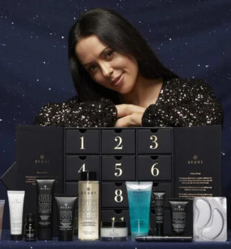 Una mujer posa con la caja y los productos del Calendario de Adviento Avant Skincare 2024