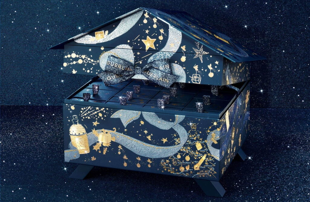 La caja del Calendario de Adviento Guerlain 2024 con forma de casita y un diseño de cielo nocturno estrellado