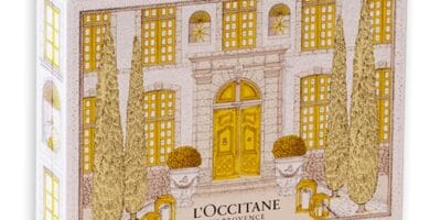 La caja del Calendario de Adviento L'Occitane 2025, que muestra una fachada flanqueada por pinos en tonos amarillo y blanco