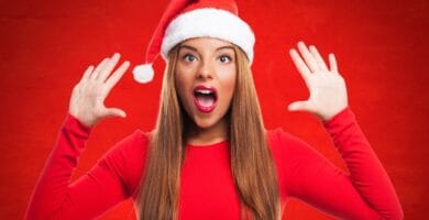 Una modelo gorro de Papá Noel y con fondo rojo pone cara de sorpresa