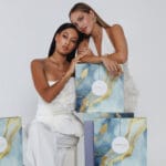 Dos modelos posan con joyas y la caja del calendario de Adviento Heideman