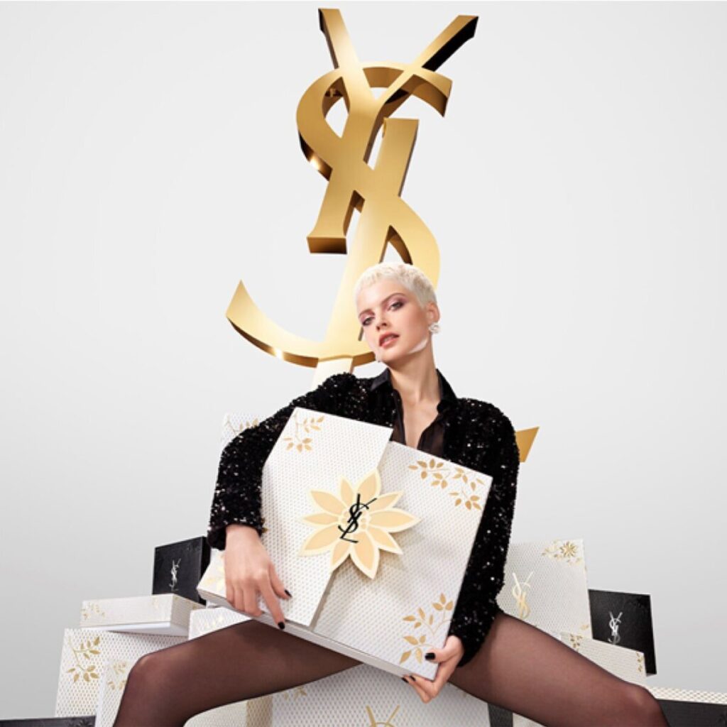 Una modelo sujeta la caja del Calendario de Adviento Yves Saint Laurent 2024 bajo el logo de la marca