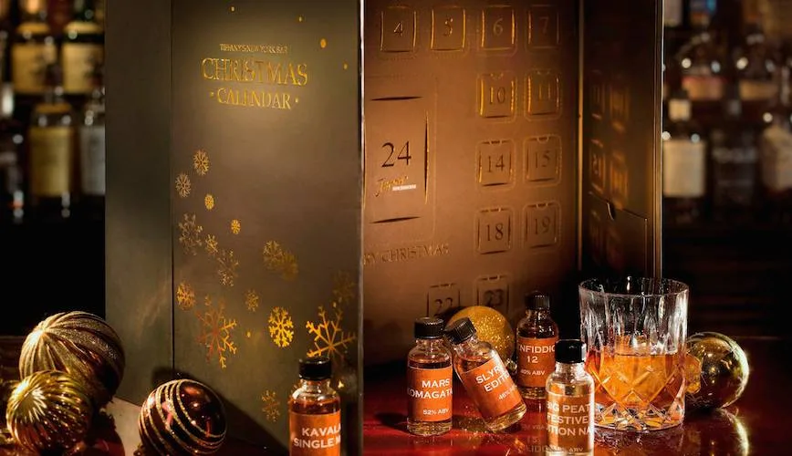 Botellines y una copa de whisky junto a un calendario de Adviento de esta bebida alcohólica